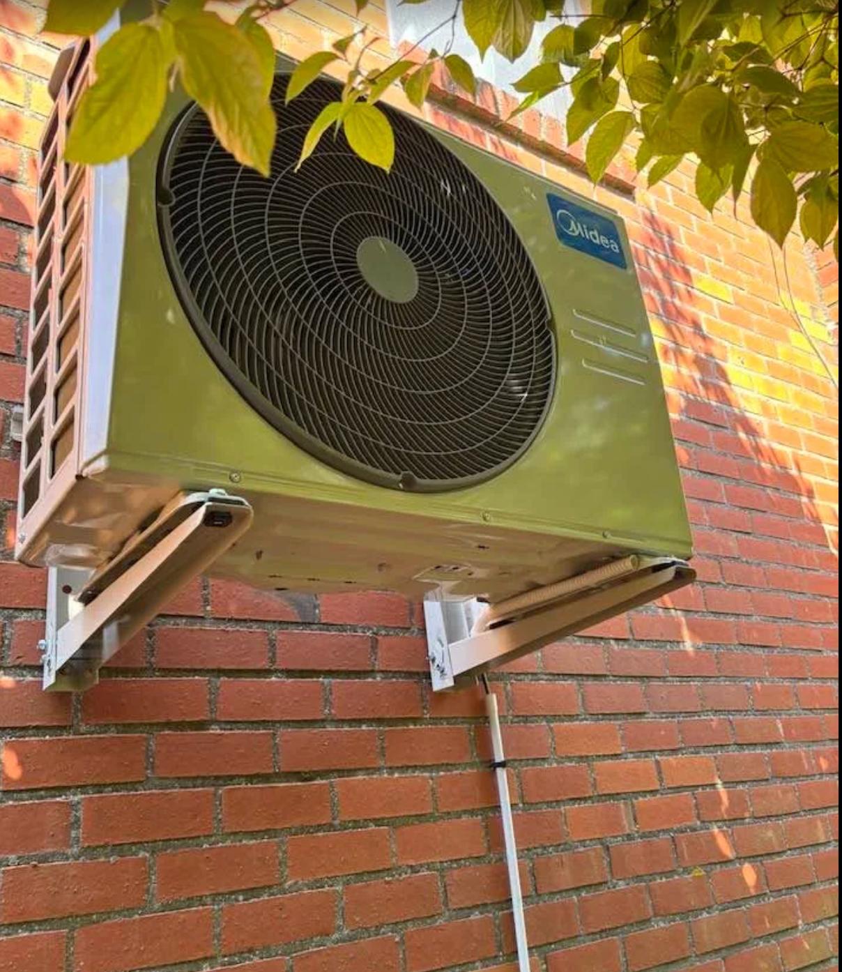 Unité extérieure de climatisation Midea fixée sur mur en brique par un bricoleur vérifié Plamby à Paris